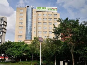 A multi-story building with a prominent glass elevator shaft, a large sign with contact information, and surrounding greenery. - Greentree Alliance Hotel Foshan Nanhai District Pingzhou Yuqi Street (Foshan)