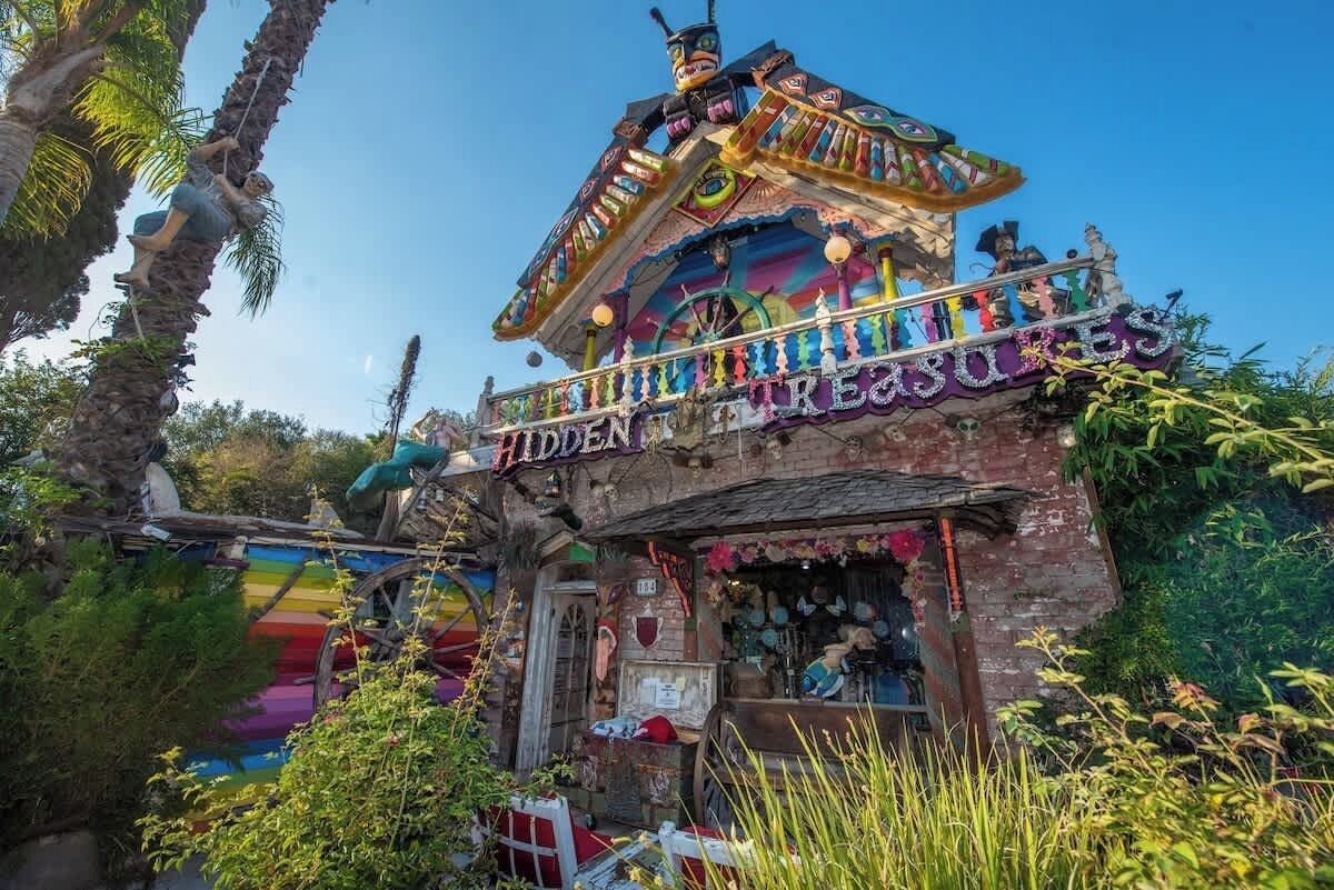 Een kleurrijk, eclectisch gebouw met een bord waarop staat: 'Hidden Treasure'.