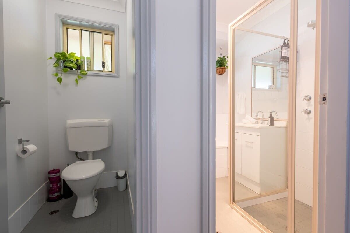 Een badkamer met toilet, een raam en een douchecel met een glazen deur.