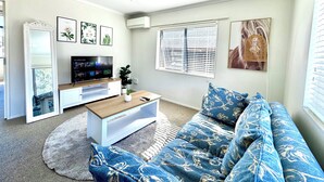 Een woonkamer met een televisie, bank, salontafel en decoratieve objecten.