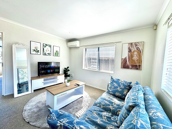 A living room with a TV, sofa, coffee table, and decorative items.