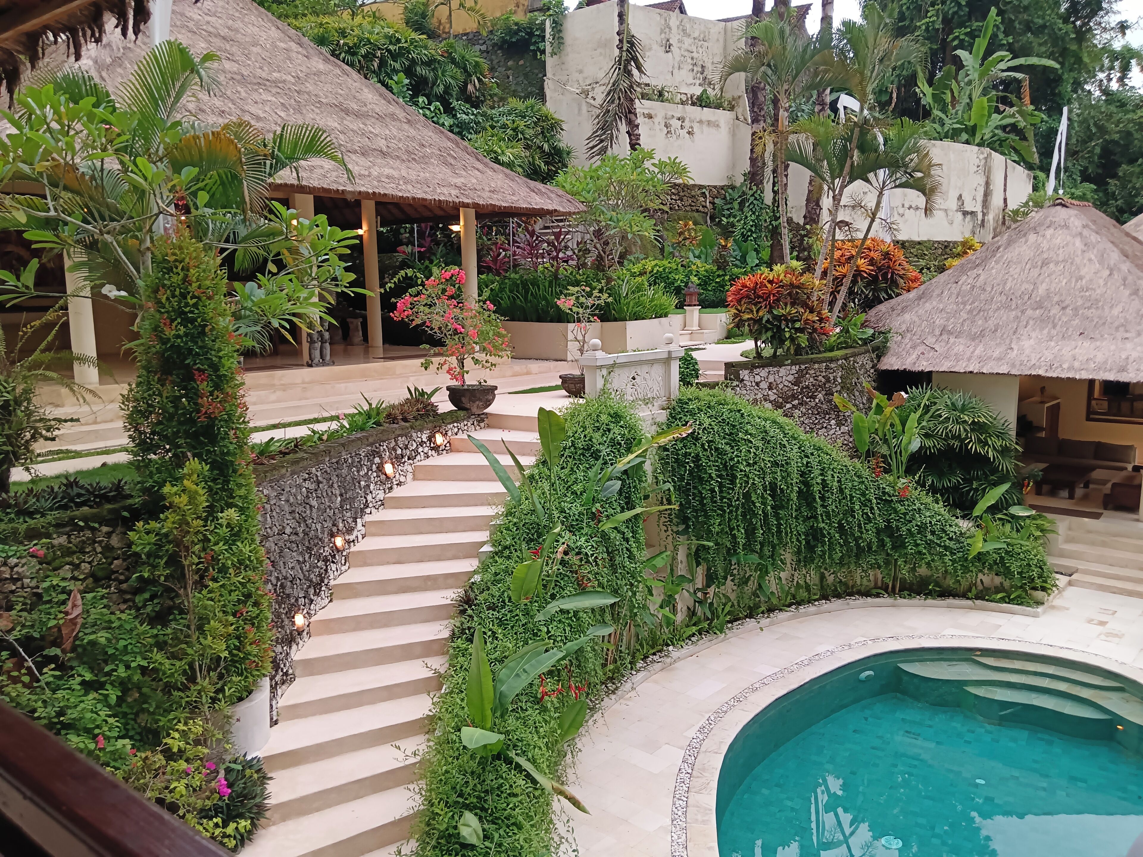 Ein Resort mit Pool, strohgedeckten Gebäuden und üppiger Vegetation.