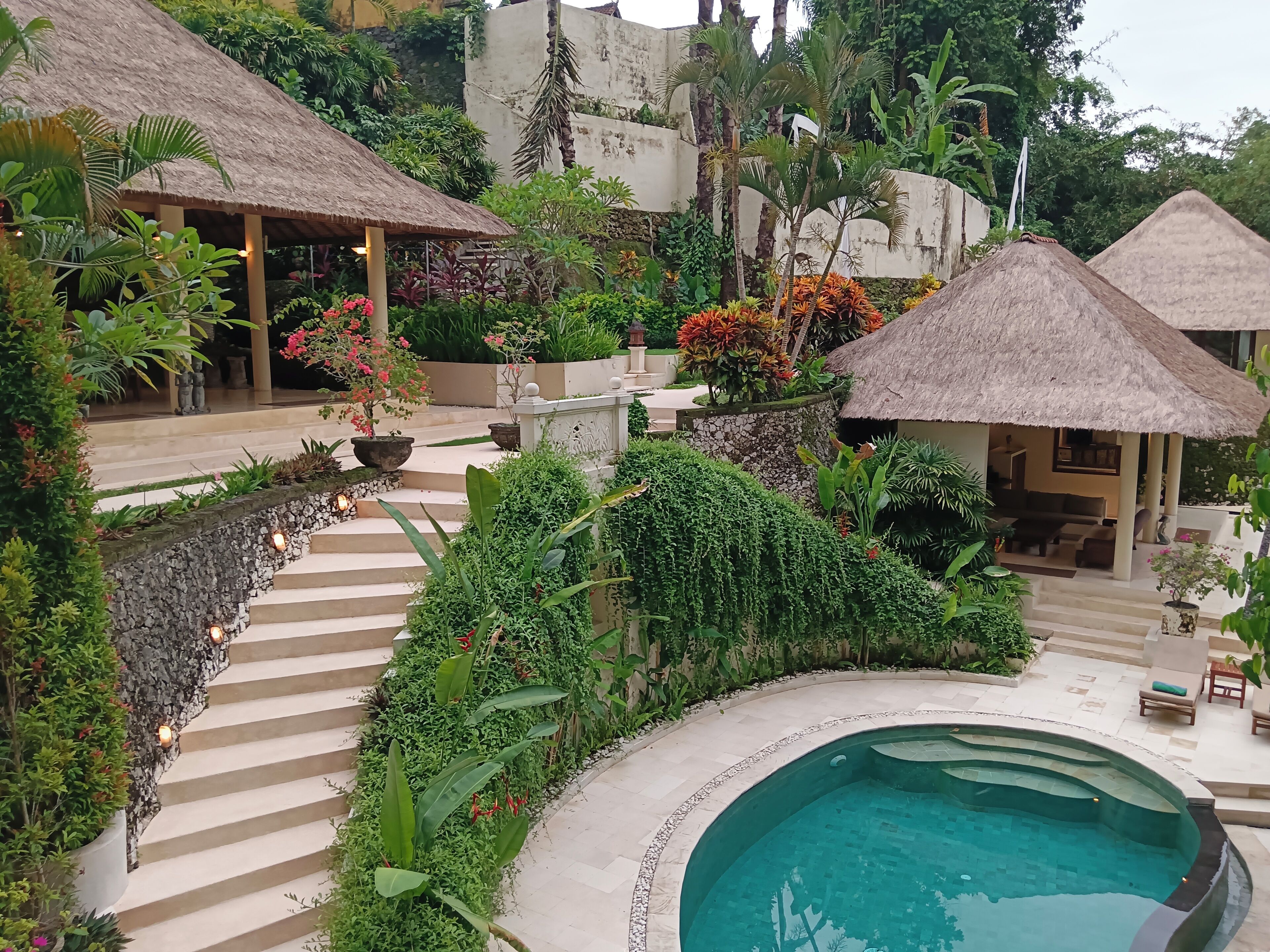 Ein Resort mit Pool, strohgedeckten Gebäuden und üppiger Vegetation.