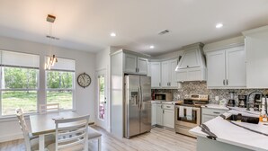 Una cocina moderna con armarios blancos, un refrigerador de acero inoxidable, un microondas y una isla grande con un lavamanos.