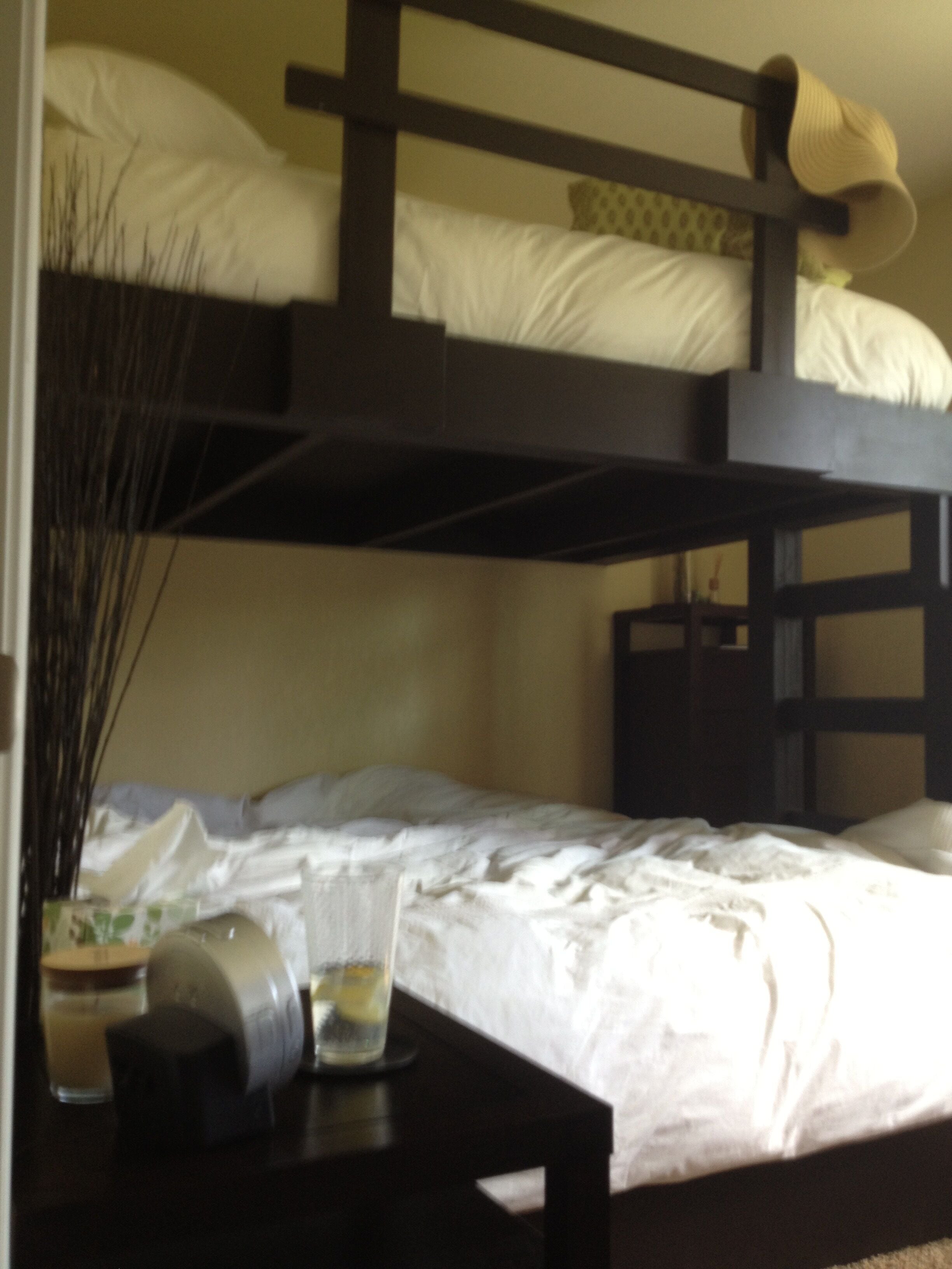 A bunk bed room with a small table and a vase of dried plants.