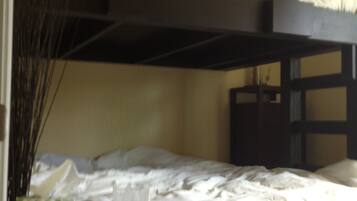 A bunk bed room with a small table and a vase of dried plants.