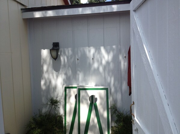 A white wooden fence with a green gate, a wall-mounted light fixture, and some greenery at the base. - Beautiful Wisconsin Beach Retreat Lake Lucerne (Crandon)