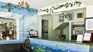 Zona de recepció amb mural d'un estany i lotus, un sofà de pell negra i una taula de cafè de vidre.