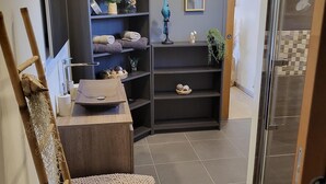 Een badkamer met een houten wastafelmeubel, planken met handdoeken, een kleine plant en een decoratief object.