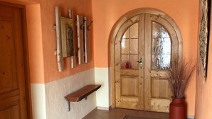 A hallway with a wooden door, a wooden shelf, and a potted plant. - Apartment 'Haus Peschl Fewo 1' with Shared Terrace, Shared Garden and Wi-Fi (Neureichenau)