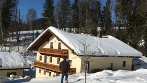 A snow-covered house with a balcony, surrounded by trees. - Apartment 'Haus Peschl Fewo 1' with Shared Terrace, Shared Garden and Wi-Fi (Neureichenau)
