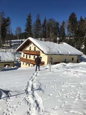 Una casa cubierta de nieve con un balcón, rodeada de árboles.