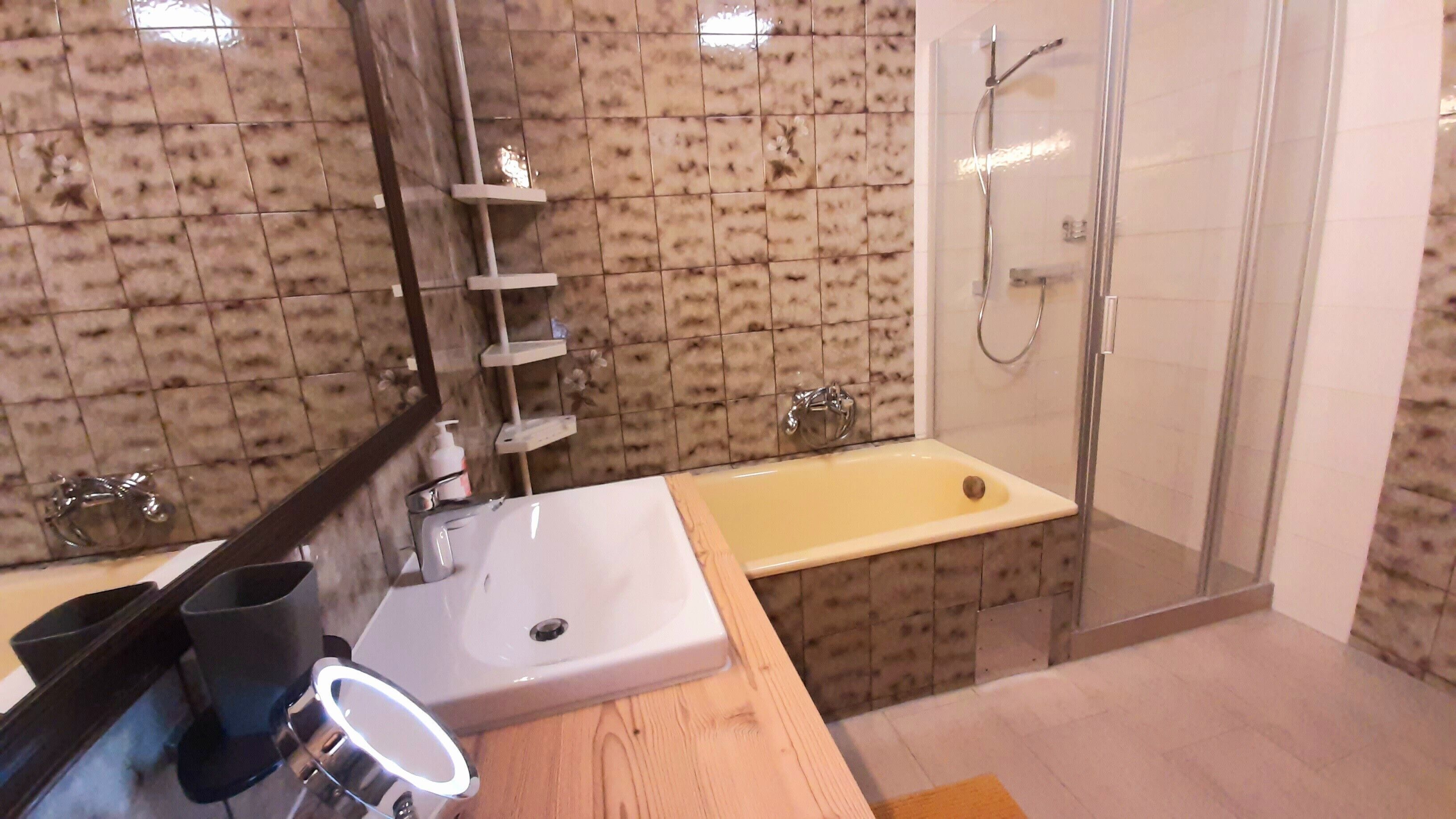 A bathroom with a sink, mirror, and shower.