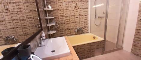 A bathroom with a sink, mirror, and shower.