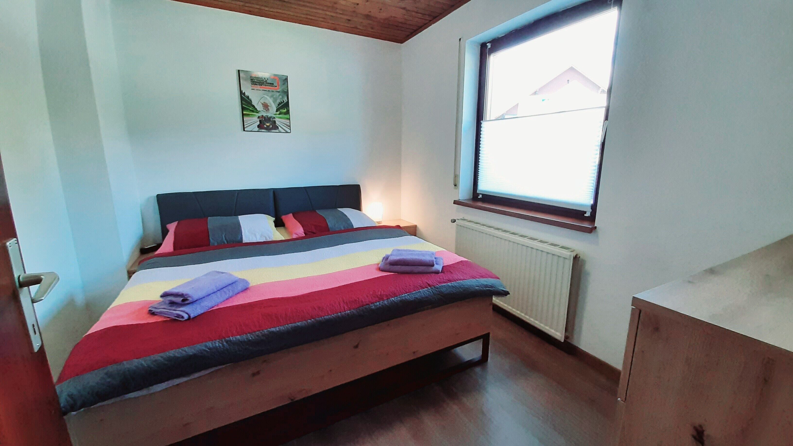 Une chambre à coucher avec un lit, un radiateur, une fenêtre et une porte.