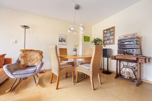 A dining area with a round table, wicker chairs, a fur throw, a floor lamp, a wall-mounted picture, and a vintage radio on a wooden table. - Apartment 'Fewo Sonnenschein' with Balcony and Wi-Fi (Hannover)