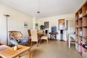 A living room with a dining table, chairs, a sofa, a bookshelf, and a lamp. - Apartment 'Fewo Sonnenschein' with Balcony and Wi-Fi (Hannover)
