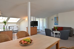 Una sala de estar moderna con comedor, televisor y balcón.