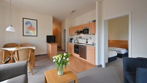 A modern apartment with a dining area, kitchenette, and a bedroom.