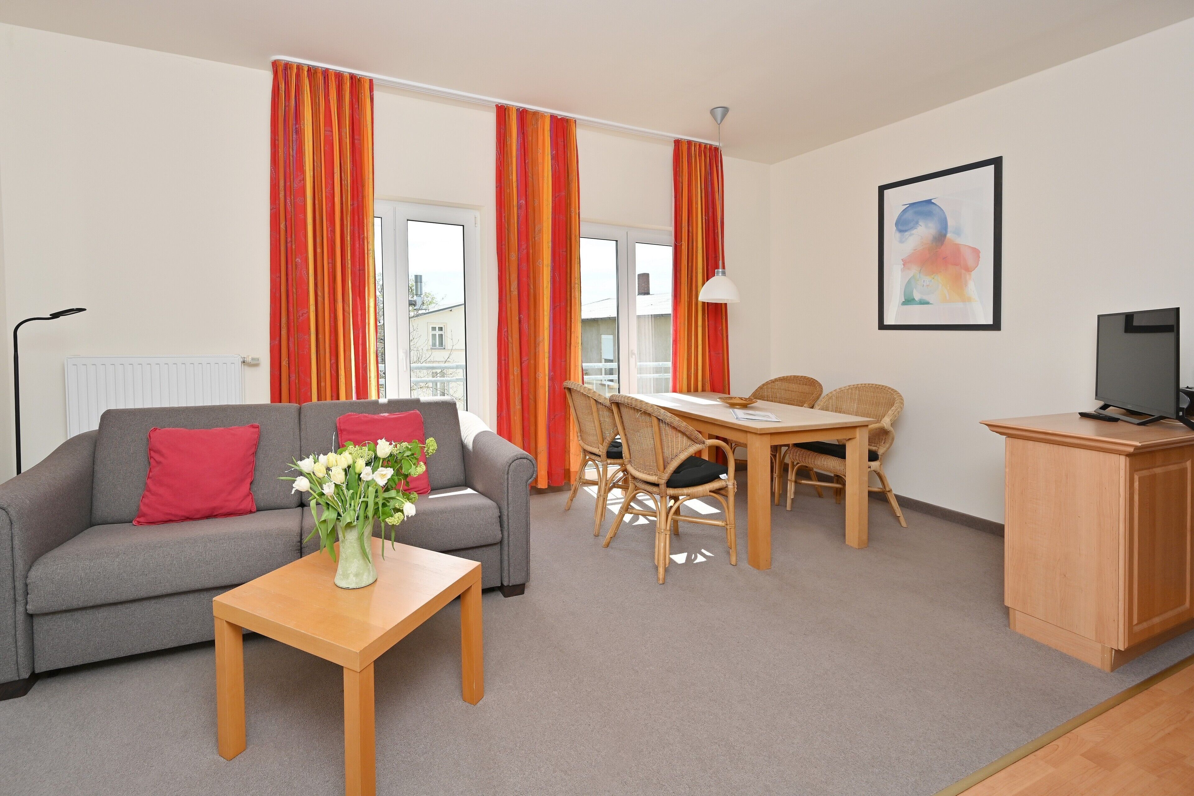 Ein möbliertes Wohnzimmer mit Sofa, Couchtisch, Esstisch und Stühlen.