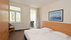 Une chambre d’hôtel avec un lit, une chaise, une fenêtre et un tableau au mur.
