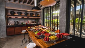 A buffet with a variety of fruits and desserts, a coffee station, and a view of the outdoors through large windows. - Anyu Hotel Sanya (Sanya)