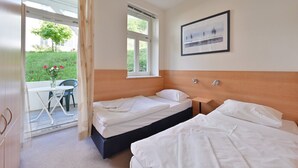 Una camera da letto con due letti, una finestra, un comodino e un quadro appeso alla parete.
