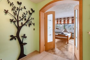 Un dormitorio con cama, puerta de madera y un adorno de árbol en la pared.