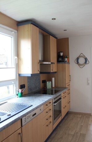 A kitchen with wooden cabinets, a built-in oven, and a window.