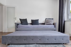 A modern bedroom with a large bed, a door, and a window with curtains.