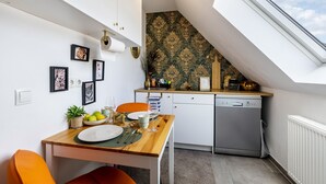 A compact kitchen with a dining area, a dishwasher, and a window with a view of the sky. - Apartment 'Deluxe' with Wi-Fi and Air Conditioning (Duisburg)
