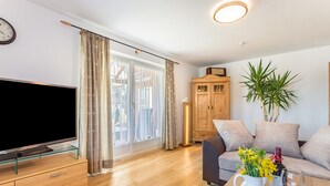 A living room with a flat-screen TV, wooden cabinet, sofa, and a plant. - Apartment 'Haus Kali' with Mountain View, Shared Terrace and Wi-Fi (Teisendorf)