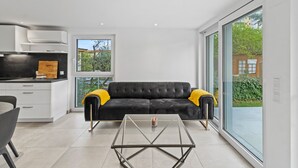A modern interior with a sofa, a glass coffee table, and a kitchen area. - Villa Jäger with Heated Pool (Available from 23.03.26) in Vienna, Private Terrace, Balcony, Wi-Fi (Wien)