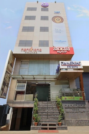 A hotel with a sign reading "Nandhini Hotels" and "Nandhini Sweets" on the ground floor. - La Sara Comforts (Bengaluru)