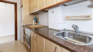 Eine Küche mit beigen Schränken, einer Granit-Arbeitsplatte, einer Edelstahl-Spüle und einer Holz-Arbeitsplatte.