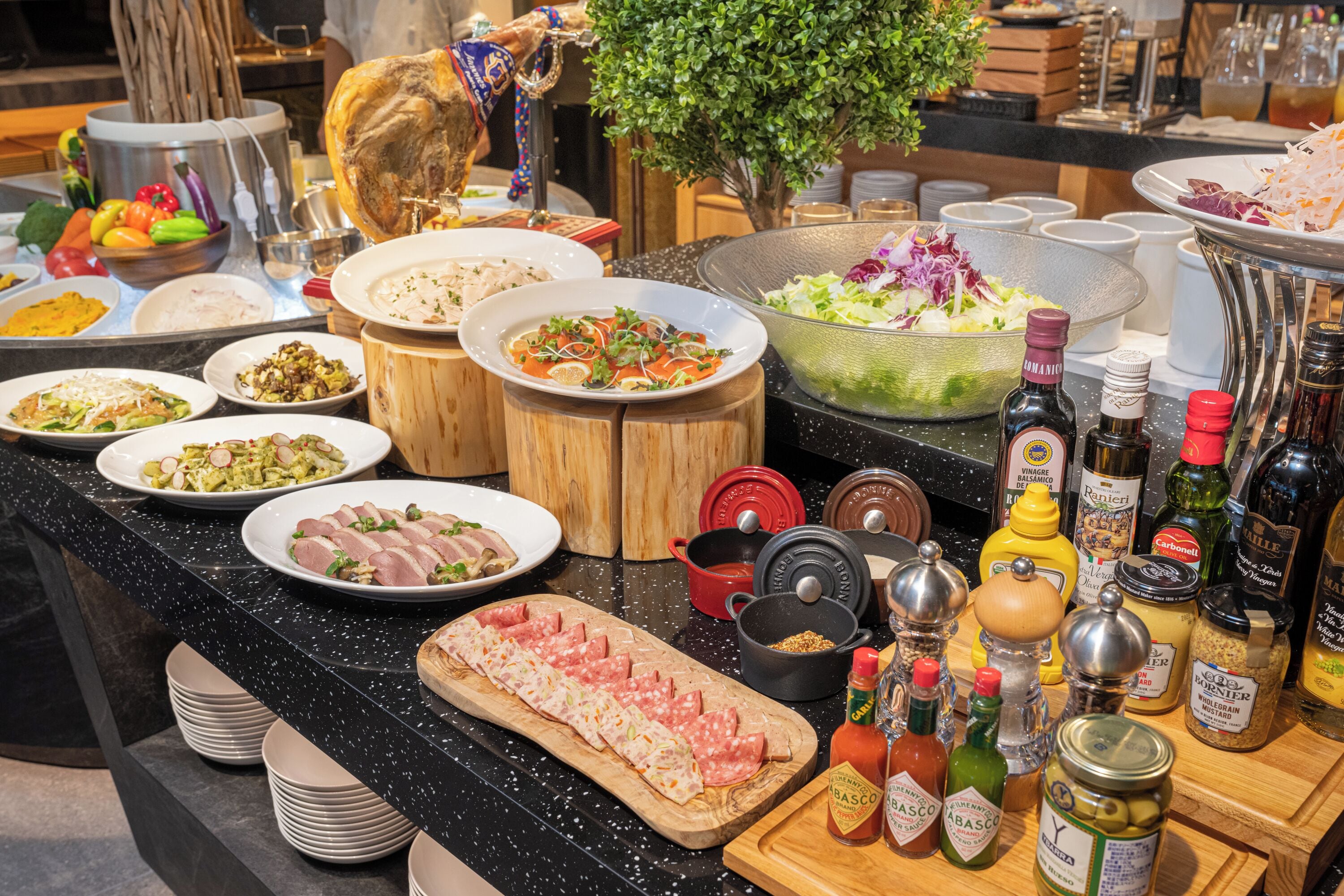 A buffet spread with various dishes, condiments, and cooking utensils.