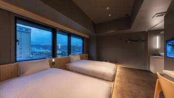 A hotel room with two beds, a desk, a TV, and a large window offering a city view.