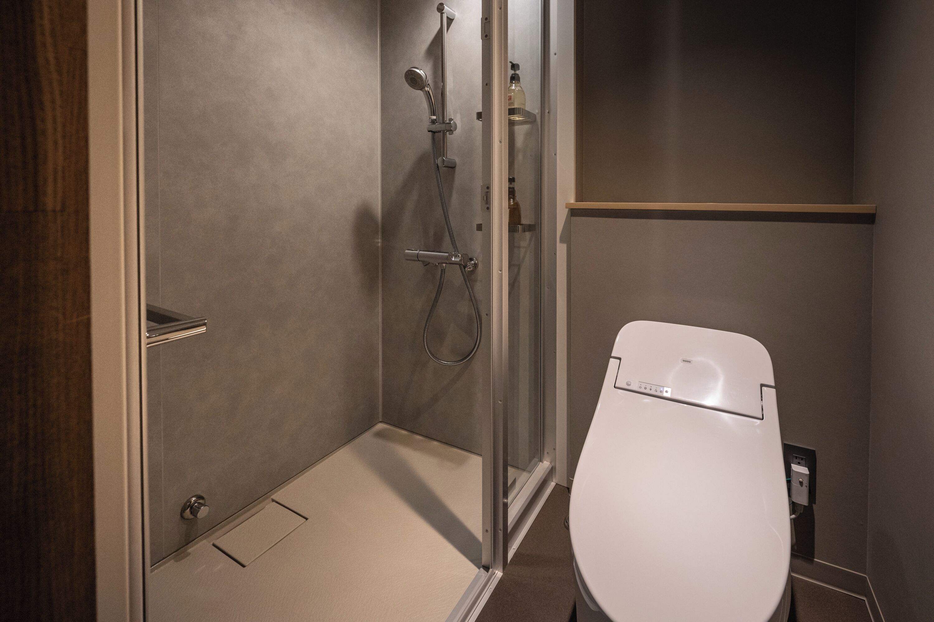 Un baño con ducha, inodoro y cabina de ducha acristalada.