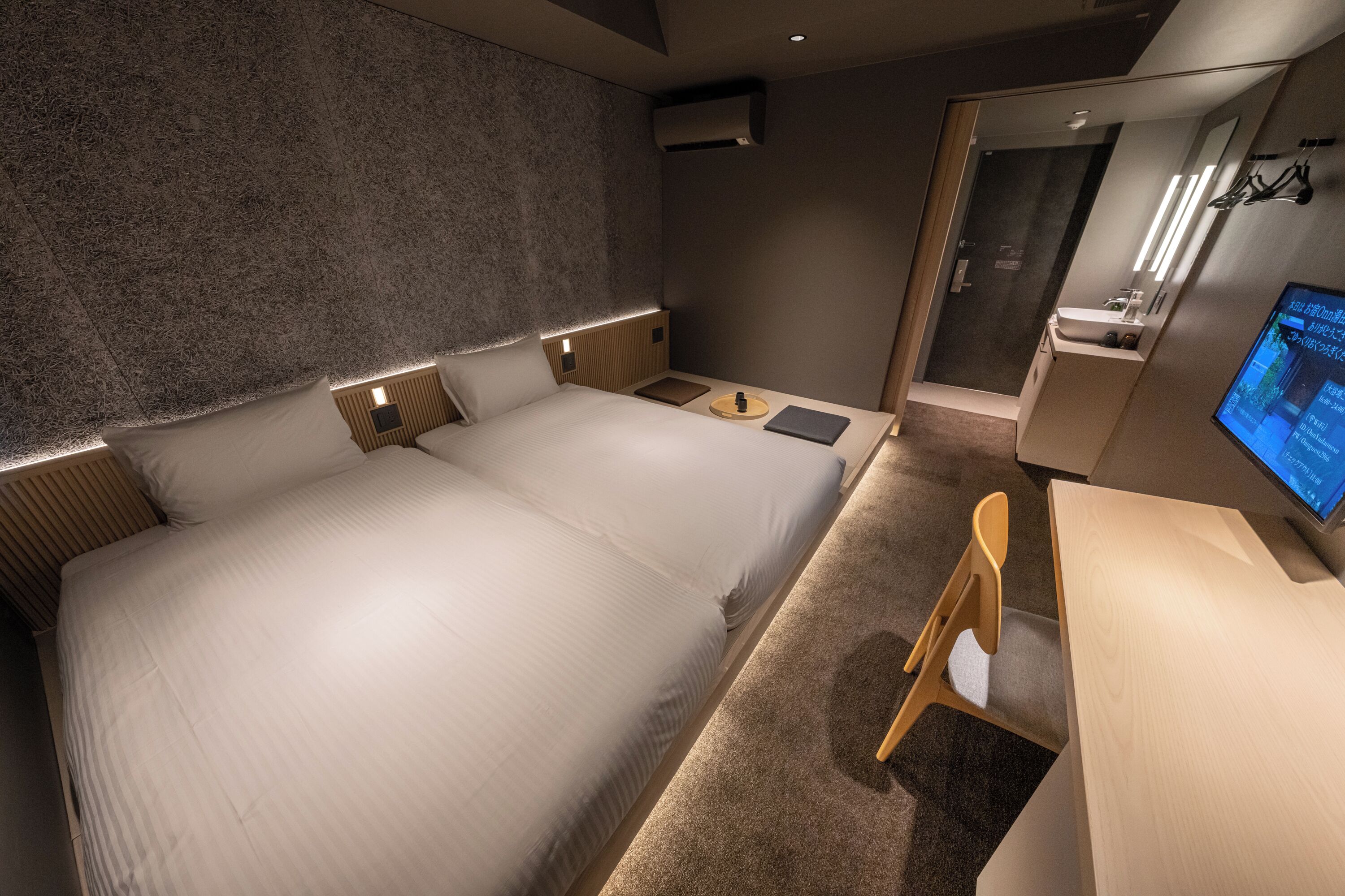 Une chambre d’hôtel moderne avec un grand lit, des tables de chevet, un bureau et une télévision.