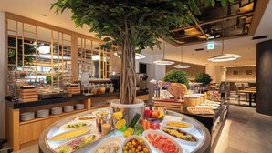 Un bufé con diversas opciones de comida, un árbol grande y una decoración de estilo moderno.