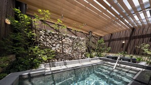 Una piscina con pared de piedra y techo de madera.