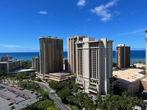 A high-rise hotel with multiple floors, a parking lot, and a view of the ocean.