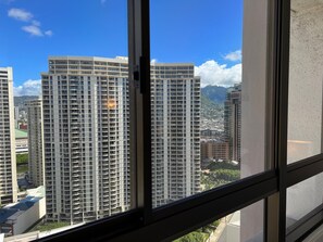 A high-rise building with multiple floors and balconies, viewed through a window with a black frame.