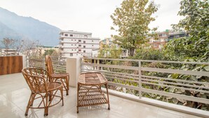 A balcony with wicker furniture and a view of a cityscape with buildings and mountains in the background. - Treebo Shree Krishnam Residency (Thane)