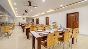 A conference room with multiple tables and chairs, ceiling fans, and recessed lighting. - Treebo Shree Krishnam Residency (Thane)