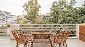 A balcony with wicker furniture, a view of buildings, and a tree. - Treebo Shree Krishnam Residency (Thane)