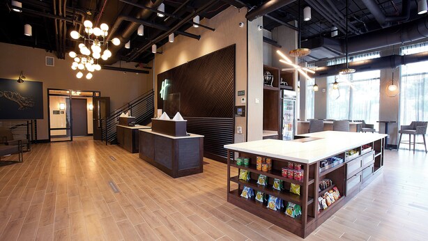 A modern hotel lobby with a reception desk, a seating area, and a snack bar. - Holiday Inn Louisville Downtown (Louisville)