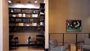 A modern library with bookshelves, seating, and a painting on the wall. - Holiday Inn Louisville Downtown (Louisville)