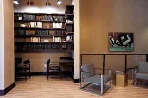 Una biblioteca moderna con estanterías, asientos y un cuadro en la pared.