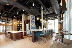 Zona de bar moderna con una barra larga, diversas opciones de asientos y equipo de cocina a la vista.